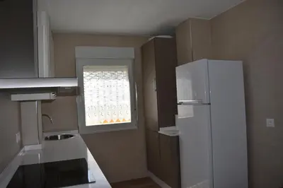 a small kitchen with a white refrigerator and a window at Vivienda de Uso Turístico ABELLA in Matarrosa del Sil