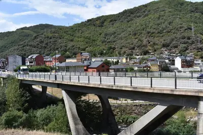 a bridge over a river with a town and a mountain at Vivienda de Uso Turístico ABELLA in Matarrosa del Sil