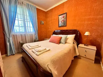 a bedroom with a bed with orange walls and a window at VILLA DAVID in Horta