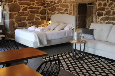 a bedroom with a bed and a couch and tables at Apartamentos Villa Maceira in Covelo