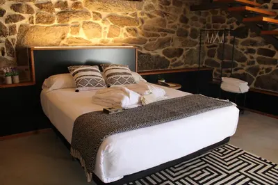 a large bed in a room with a stone wall at Apartamentos Villa Maceira in Covelo