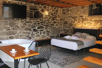 a bedroom with a bed and a tub and a table at Apartamentos Villa Maceira in Covelo