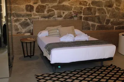 a bed in a room with a stone wall at Apartamentos Villa Maceira in Covelo