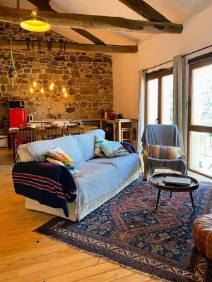 a living room with a couch and a stone wall at Farm house in Ribeira Sacra in O Carballo
