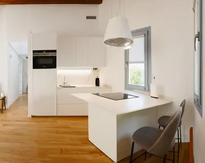 a kitchen with white cabinets and a counter and two chairs at O Souto da Aldea Ribeira Sacra Parada de Sil in Parada del Sil