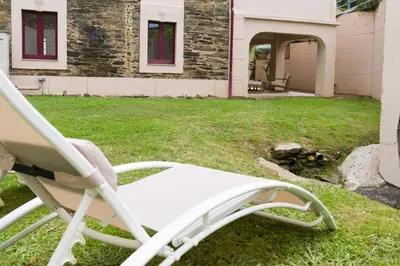 a white rocking chair in front of a house at Apartamento con jardín en San Sadurniño in Santa María La Mayor del Rosario