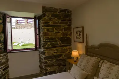 a bedroom with a stone wall and a bed and a window at Apartamento con jardín en San Sadurniño in Santa María La Mayor del Rosario