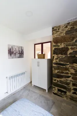a room with a stone wall and a white cabinet at Apartamento con jardín en San Sadurniño in Santa María La Mayor del Rosario