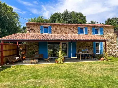 a stone house with blue windows and a patio at seixurra 31 in A Coruña