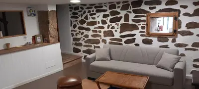 a living room with a couch and a rock wall at Casa da Eiriña in Amés