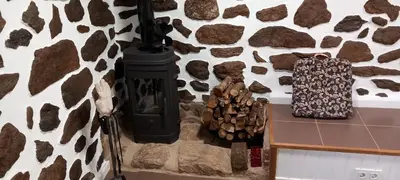 a stone wall with a wood stove in a room at Casa da Eiriña in Amés