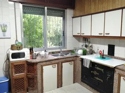 a kitchen with white cabinets and a large window at A CASA DOS AVÓS in Celanova