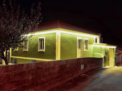 a green house at night with a brick wall at Casa de Ribeira Sacra in Pantón