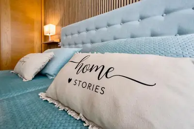a bed with a pillow with home stories written on it at Muralla & Views by Lugo Collection in Lugo