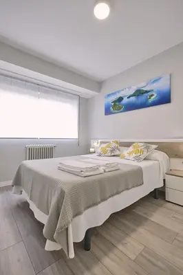 a white bedroom with a large bed with a window at La Casa de Julia Apartamento nuevo y céntrico in Santiago de Compostela