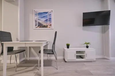 a dining room with a white table and a tv at La Casa de Julia Apartamento nuevo y céntrico in Santiago de Compostela