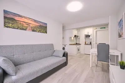 a living room with a gray couch and a kitchen at La Casa de Julia Apartamento nuevo y céntrico in Santiago de Compostela