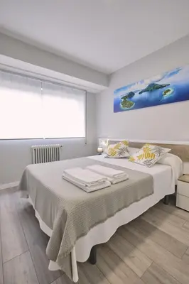 a white bedroom with a large bed with a window at La Casa de Julia Apartamento nuevo y céntrico in Santiago de Compostela