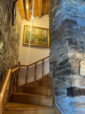 a staircase in a stone building with a painting on the wall at Habitaciones Frade in O Cebreiro