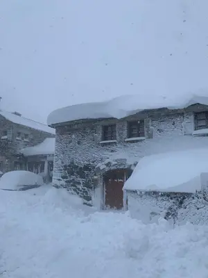 a building covered in snow with snow on top of it at Habitaciones Frade in O Cebreiro