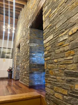 a large stone wall in a room with a wooden floor at Habitaciones Frade in O Cebreiro