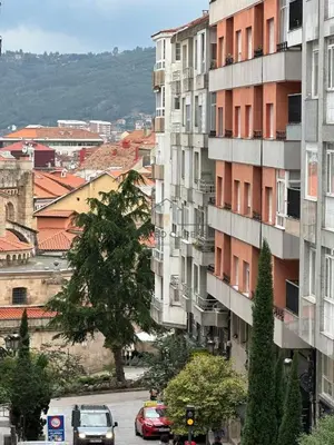 a tall building with cars parked on a city street at A Morada das Mimosas in Ourense