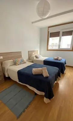 a bedroom with two beds with blue sheets and two windows at A Segunda Ronda in Melide