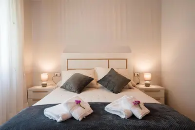 a bedroom with a bed with towels and two lamps at A DE NENO in Melide