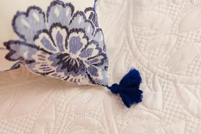 a blue and white flower pillow on a bed at A DE NENO in Melide