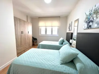 a bedroom with two beds and a cabinet at EL NORTE in Viveiro
