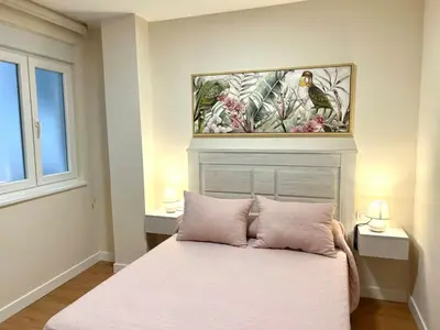 a bedroom with a bed with pink sheets and a painting on the wall at EL NORTE in Viveiro