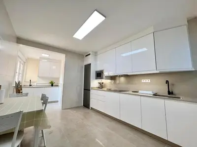 a large kitchen with white cabinets and a table at EL NORTE in Viveiro