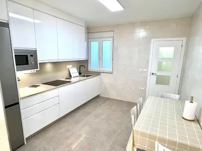 a small kitchen with white cabinets and a table at EL NORTE in Viveiro