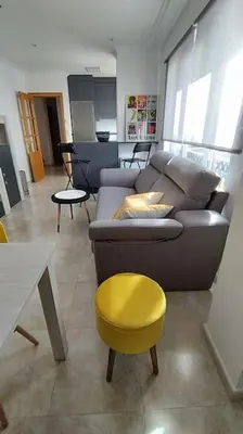 a living room with a couch and a yellow stool at Apartamento en Foz. Primera Línea Playa Rapadoira in Foz
