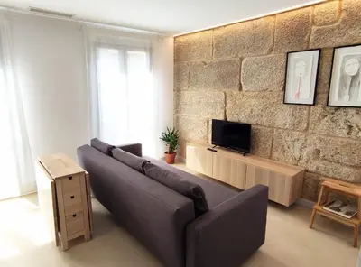 a living room with a couch and a tv on a brick wall at Cánovas 21 in Carballino