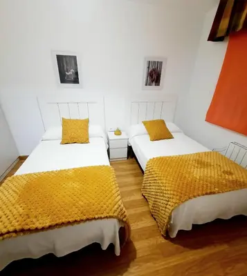 two beds in a room with white walls and yellow pillows at Apartamento Obao in Ribadeo