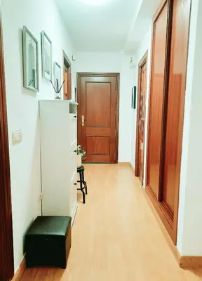 a hallway with a black ottoman and a wooden door at Apartamento Obao in Ribadeo