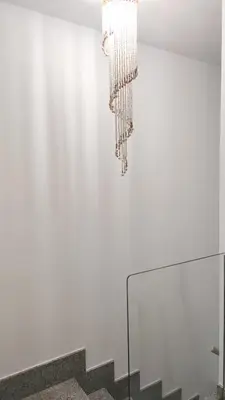 a chandelier hanging from a white wall with stairs at Suite Playa in Miño