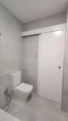 a bathroom with a toilet and a glass door at Suite Playa in Miño