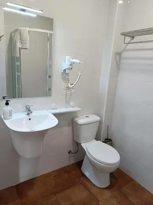 a white bathroom with a toilet and a sink at Albergue Miraiso in Arzúa