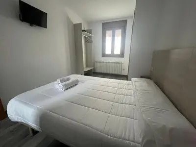 a large white bed in a room with a window at Albergue Miraiso in Arzúa