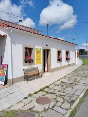 a white building with a bench in front of it at Albergue Miraiso in Arzúa