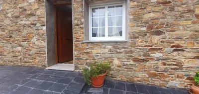 a brick building with a window and a potted plant at ALOJAMIENTOS EL CASTRO in Taramundi
