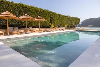 a swimming pool with umbrellas and chairs and a pool at Malates Slow Boutique Hotel in Foz