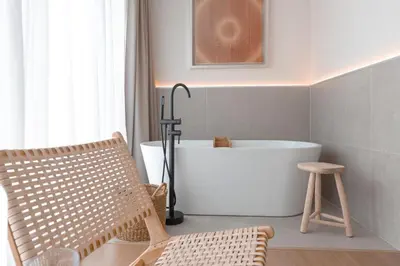 a bathroom with a bath tub and a chair at Malates Slow Boutique Hotel in Foz