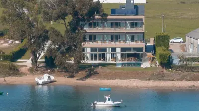 a boat in the water in front of a large house at Malates Slow Boutique Hotel in Foz
