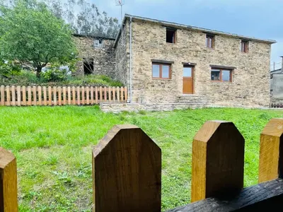 a stone house with a fence in front of it at Casa Neto Goje in San Tirso de Abres