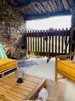 a person sitting on a bed in a room with a fence at Casa Neto Goje in San Tirso de Abres