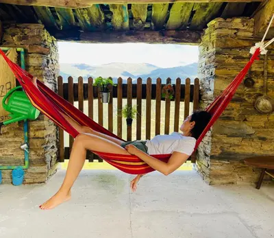 a woman sitting in a red hammock at Casa Neto Goje in San Tirso de Abres