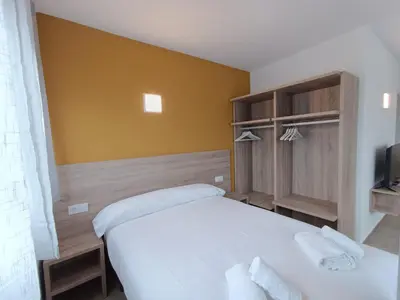 a bedroom with a white bed and a yellow wall at Apartamentos Turísticos Pontepedriña by Bossh! Hotels in Santiago de Compostela